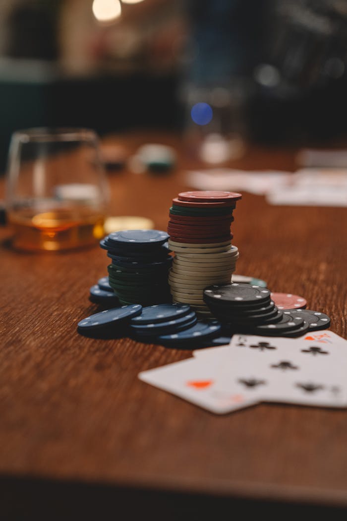 story-01 Poker chips and playing cards on a wooden table with a whiskey glass, emphasizing gambling and entertainment.