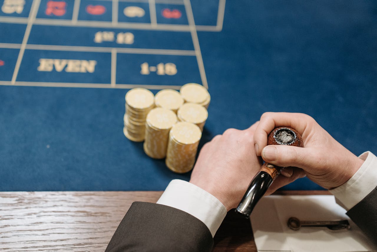Hands holding a tobacco pipe and poker chips on a casino table. Top view.